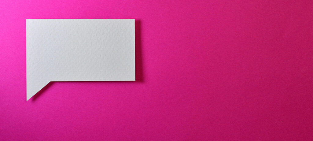 ピンク色の背景に吹き出しの形に切り抜かれた白い紙が置かれた写真