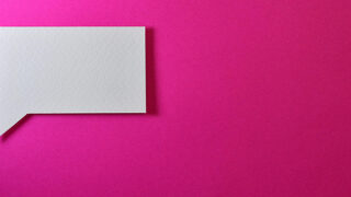 ピンク色の背景に吹き出しの形に切り抜かれた白い紙が置かれた写真